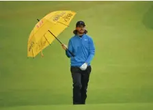  ?? GETTY IMAGES ?? ALL WET: Tommy Fleetwood tries to stay dry during yesterday’s final round of the British Open.