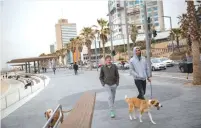 ?? ?? MEN WALK their dogs along the Tel Aviv beach promenade. (Miriam Alster/Flash90)