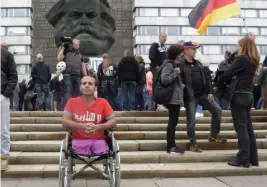  ?? — AP ?? A man wears a t- shirt with the Arabic writing ‘ No Nazis’ as he sits in a wheelchair in front of the Karl Marx statue in Chemnitz, eastern Germany, on Saturday after several nationalis­t groups called for marches protesting the killing of a German man last week, allegedly by migrants from Syria and Iraq.