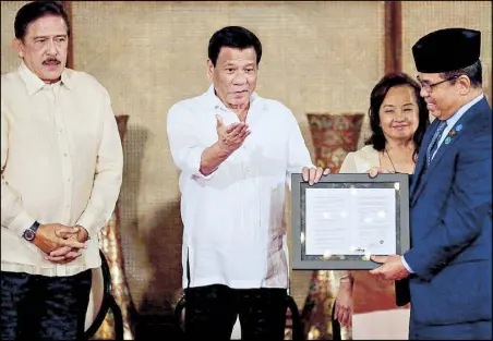  ?? KRIZJOHN ROSALES ?? President Duterte presents to MILF chairman Murad Ebrahim the signed Organic Law for the Bangsamoro Autonomous Region in Muslim Mindanao during a ceremony at Malacañang yesterday. Joining them are Senate President Vicente Sotto III and Speaker Gloria Macapagal-Arroyo.