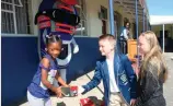  ?? Photos: Alida de Beer ?? Deagan Erfmann hands over a pair of takkies to Amber Switch, a Grade 1 learner. His sister, Cienna, was there to help.