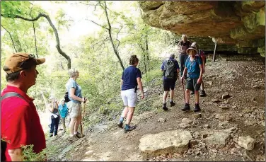  ?? NWA Democrat-Gazette/FLIP PUTTHOFF ?? Hikers explore a bluff shelter June 8 along the Bench Rock Trail near Beaver Lake at Indian Creek park. The 1.1-mile oblong loop meanders through forest and along bluffs.