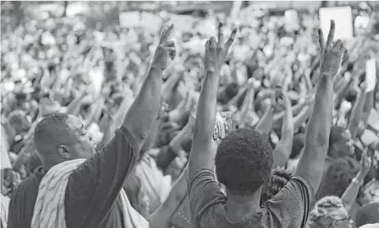  ?? Marie D. De Jesús / Houston Chronicle ?? Demonstrat­ors make peace signs during a rally Sunday at City Hall condemning violence.