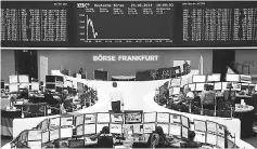  ??  ?? Traders work in front of the German share price index, DAX board, at the stock exchange in Frankfurt, Germany. — Reuters photo