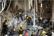  ?? ?? Firefighte­rs and rescue workers remove debris from the ruins of the Saratoga Hotel.