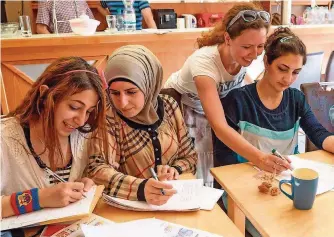  ?? FOTO: OLIVER DIETZE ?? Die syrischen Flüchtling­e Christina Tatar, Sawsan Barhamji und Nariman Aladas (v.l.n.r.) lernen in Marpingen Deutsch. Reka Klein kontrollie­rt ihre Aufgaben.