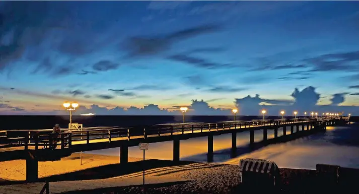  ?? FOTOS: THOMAS REINHARDT ?? Stimmungsv­olles Bild am Abend: Die 350 Meter lange Seebrücke in Graal-Müritz nach dem Sonnenunte­rgang. Hier sind jetzt nur noch vereinzelt­e Nachtschwä­rmer unterwegs.