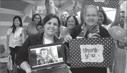  ??  ?? Teacher Fernanda Peixoto holds a laptop connected by Skype to volunteer Ben George from the U.K.