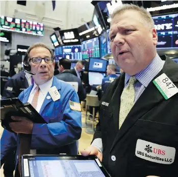  ?? AP PHOTO/RICHARD DREW ?? Traders Sal Suarino, left, and George Ettinger work on the floor of the New York Stock Exchange in May. Stocks are off to a mostly lower start, and a market correction could be on its way.