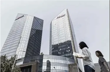  ?? — Bloomberg ?? Big plans: Pedestrian­s walking past the HNA building in Beijing. The firm has been expanding its presence in Hong Kong, spending about US$3.5bil earlier this year.