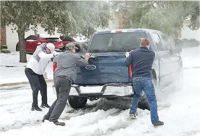  ??  ?? Residents help a driver get out of snow on a road in Round Rock, Texas. — AFP