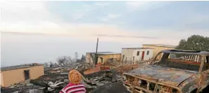  ??  ?? In the line of fire: A resident of Knysna looks at the houses burnt down by rapid wildfires