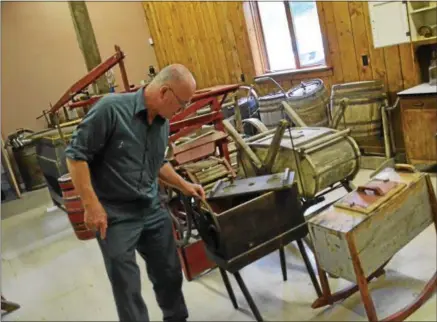  ??  ?? Red Gate Farms owner Bruce Rivington demonstrat­es one of his antique butter churns.