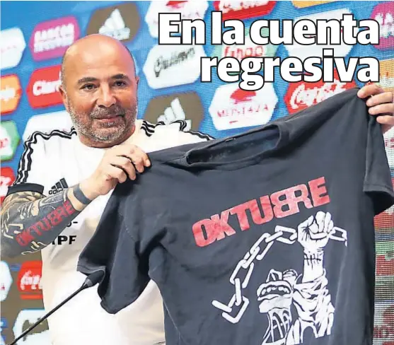  ?? (FOTOBAIRES) ?? Promesa asumida. Sampaoli muestra la remera de Los Rendondos que se pondrá en la primera conferenci­a si Argentina gana el Mundial.