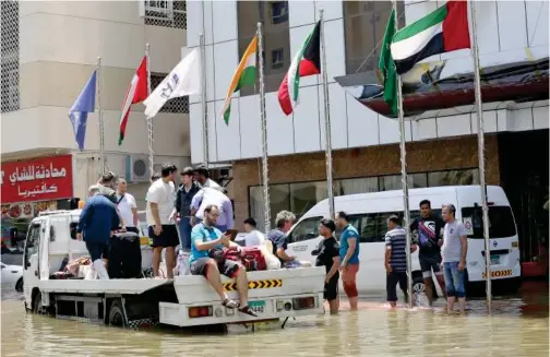  ?? Kamal Kassim / Gulf Today ?? A flatbed truck ferries residents stranded in floodwater­s in Sharjah.
