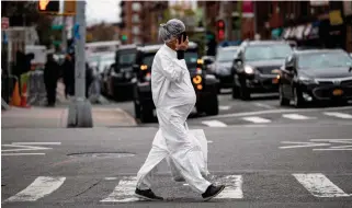  ?? JOHANNES EISELE
AFP/GETTY IMAGES ?? A pregnant woman wearing a haz-mat suit walks in New York City on Monday. The Centers for Disease Control listed six new symptoms of COVID-19 on its website on April 18.