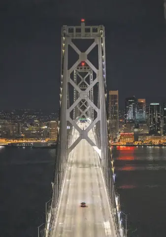  ?? Carlos Avila Gonzalez / The Chronicle ?? A car makes its way across the Bay Bridge after midnight Tuesday as San Francisco shut down following an order to shelter in place. Six Bay Area counties have issued the stayhome order.