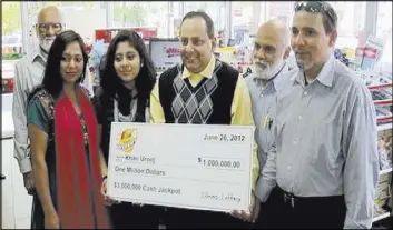  ?? COURTESY OF WMAQ-TV VIA AP ?? Urooj Khan, center, holds a ceremonial check June 2012 in Chicago for $1 million as winner of an Illinois instant lottery game. At left, is Khan’s wife, Shabana Ansari. Khan died suddenly on July 20, 2012, days before he was to collect his winnings.