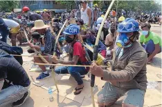  ?? ASSOCIATED PRESS ?? Anti-coup protesters prepare makeshift bows and arrows to confront police in Thaketa township in Yangon, Myanmar, on Saturday, when dozens were killed by police across the country.