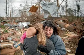  ?? AP ?? Carol Dean, right, cries while embraced by Megan Anderson and her 18-month-old daughter Madilyn, as Dean sifts through the debris of the home she shared with her husband, David Wayne Dean, who died when a tornado destroyed the house in Beauregard, Alabama.