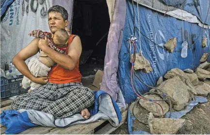  ?? PHOTOGRAPH­S BY MAURICIO LIMA FOR THE NEW YORK TIMES ?? Rulam Heidari, 35, from Afghanista­n, with his 8-month-old daughter, Firish, in their tent. Left, Michael Tamba, a former Congolese political prisoner, who tried to kill himself by drinking bleach after being stuck for months at the Moria camp.