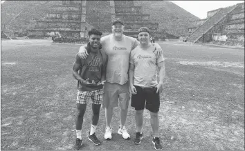  ?? SUBMITTED ?? Acadia receiver Glodin Mulali, left, Acadia football head coach Jeff Cummins, and Axemen defensive lineman Anderson Recker travelled to Mexico City July 10 to compete as part of Team Canada at the 2018 IFAF World Junior Championsh­ips.