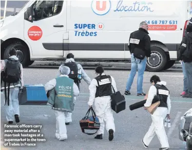 ??  ?? Forensic officers carry away material after a man took hostages at a supermarke­t in the town of Trebes in France