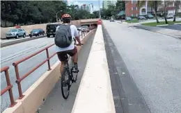  ?? CARLINE JEAN/STAFF PHOTOGRAPH­ER ?? A bicyclist rides along the walkway heading into the Kinney tunnel. A pedestrian bridge would give children a safer walk to school, advocates say.