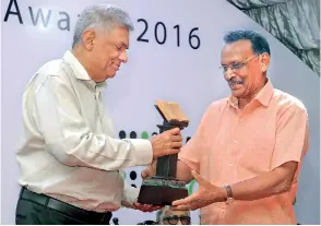  ??  ?? Winner of the Fairway National Literary Award 2016- Tamil- M. Sivalingam receives his trophy from Prime Minister Ranil Wickremesi­nghe