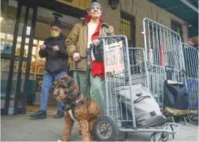  ?? AP PHOTO/BEBETO MATTHEWS ?? On Dec. 7, Aron Halberstam, right, and his dog Ralph leave after shopping at Brooklyn’s Park Slope Co-Op grocery store, where a policy requires shoppers to wear a mask on Wednesdays and Thursdays, in New York.