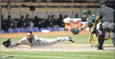  ?? THEARON W. HENDERSON / GETTY IMAGES ?? Houston infielder Marwin Gonzalez dives under the tag of Oakland catcher Josh Phegley to give the Astros a 2-1 lead in the second inning Sunday. Gonzalez came home on Jake Marisnick’s sacrifice fly.