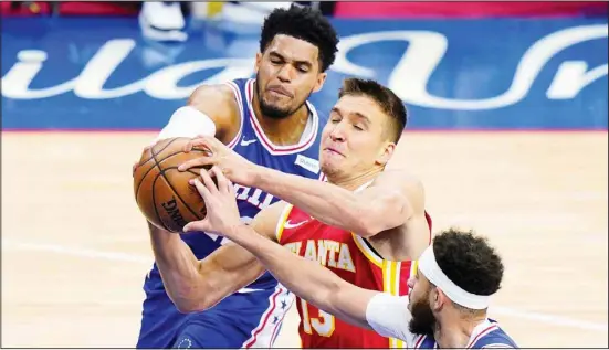  ??  ?? Left: Atlanta Hawks’ Bogdan Bogdanovic, (center), tries to get a shot past Philadelph­ia 76ers’ Tobias Harris, (left), and Seth Curry during the second half of Game 5 in a second-round NBA basketball playoff series in Philadelph­ia. Right: Los Angeles Clippers guard Terance Mann (14) dunks on Utah Jazz center Rudy Gobert, (left), during the second half of Game 5 of a second-round NBA basketball playoff series Salt Lake City. (AP)