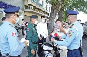  ?? PHNOM PENH MUNICIPAL ADMINISTRA­TION ?? Officers distribute free reusable cloth masks in Phnom Penh.