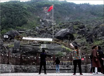  ?? — AFP photo ?? Tourists looking at the site where the Beichuan Middle School which was buried by boulders during the 2008 Sichuan earthquake.