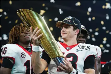  ?? The Boston Globe ?? Quarterbac­k Stetson Bennett hoisted the trophy when Georgia enjoyed a championsh­ip ride through the College Football Playoff last season.