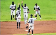  ?? JULIO CORTEZ/ASSOCIATED PRESS ?? Miami players engage in socially distanced high fives after their 4-0 victory over Baltimore on Tuesday. The Marlins hadn’t played since July 26.