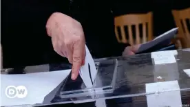  ??  ?? Человек опускает избиратель­ный бюллетень в урну для голосовани­я