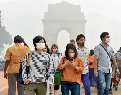  ?? PTI ?? Tourists wear masks to protect themselves from smog and air pollution that reached high levels at Rajpath in New Delhi on Sunday. —