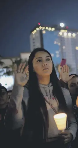  ??  ?? Mourners hold up their right hands to pledge to spread peace and at a candleligh­t vigil for the victims of Sunday night’s mass shooting near the scene of the attack just off Las Vegas Boulevard