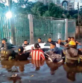  ??  ?? DAÑOS. Policías, bomberos y ciudadanos, al ayudar a sacar un auto varado.