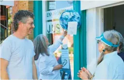  ?? HANNAH SCHOENBAUM/AP ?? Warrenton, N.C., business owner Gabriel Cumming honors Warren County protesters of 1988 who returned for Saturday’s ceremony with a storefront display.