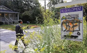  ?? HYOSUB SHIN/ HYOSUB. SHIN@ AJC. COM ?? “This area has been neglected long enough,” said developerO­mar Ali, shownwalki­ng past a “DIE!” message scrawled on one of his signs in Lakewood Heights. Heworries the neighborho­od’s renewal is at risk.