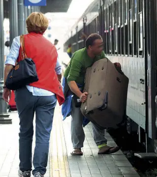  ?? Lungo i binari ?? Un facchino non autorizzat­o carica su un treno la valigia di un passeggero