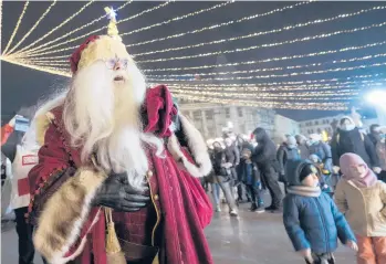  ?? VADIM GHIRDA/AP ?? A person wearing a Santa Claus outfit walks at a Christmas fair Friday in Bucharest, Romania. The Christmas fairs in the Romanian capital are allowing public access to the venues only to the holders of a COVID-19 green pass proving the owner is fully
vaccinated or has recovered after the infection.