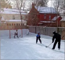  ?? Iron Sleek via AP ?? Members of the Rubin family are shown playing hockey on their backyard ice rink in the Burns Park neighbourh­ood of Ann Arbor, Mich.