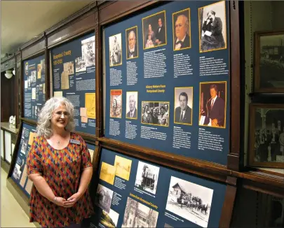  ?? Staff photos by Greg Bischof ?? ■ Melissa Nesbitt, archival manager for the Southwest Arkansas Regional Archives, stands near a display commemorat­ing the archive collection’s 40th anniversar­y, above. The Hempstead County Historical Society took the lead in founding SARA in 1978. Nesbitt, below, inspects material contained in one of the center’s research rooms.