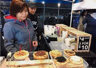  ?? — AP ?? Sweet indulgence: A vendor selling coconut cake snacks with various toppings from Indonesia.