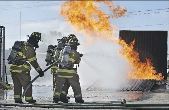  ?? ED KAISER ?? Three and a half months into their training, members of Edmonton Fire Rescue Services Recruit Class 148 attack a propane-fuelled fire Friday.