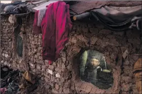  ?? ?? A child looks out of a window of his home Dec. 7 in a neighbourh­ood where many internally displaced people have been living for years in Kabul.