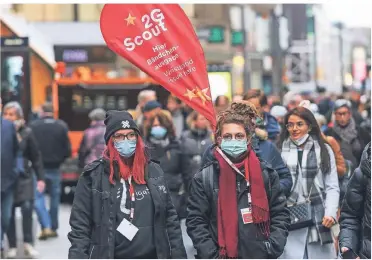  ?? FOTO: HANS-JÜRGEN BAUER ?? Auf der Schadowstr­aße verteilten Jasmin (l.) und Sophia kostenlose Bändchen für die Weihnachts­märkte, aber erst nach einer 2G-Kontrolle.